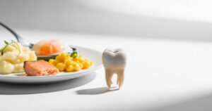 a single crowned tooth next to a small plate of soft foods