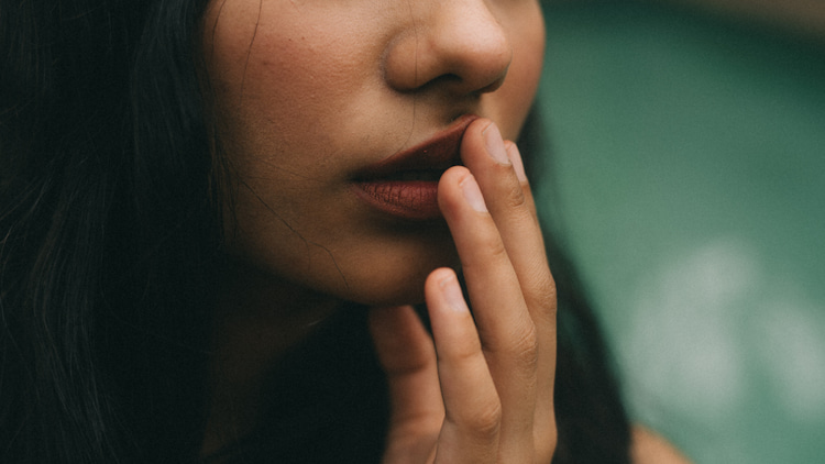 a woman gently touching her lip as it's still numbed after a dental treatment.