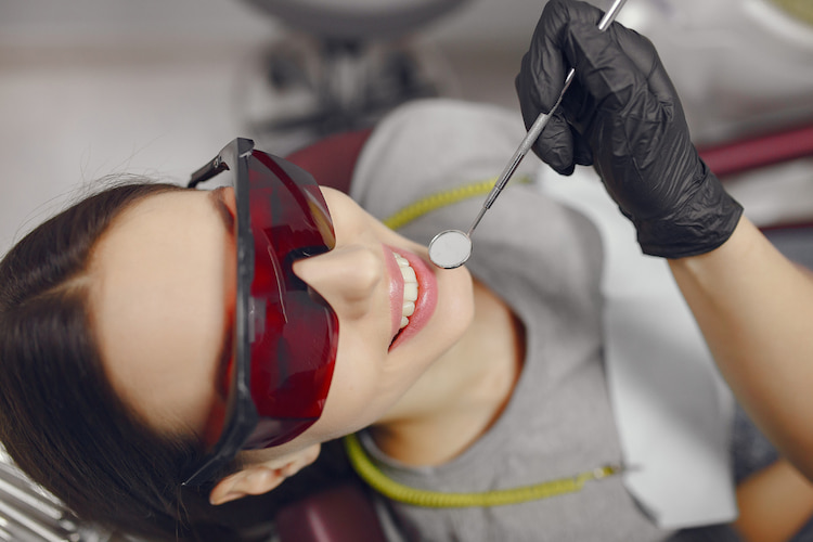 a woman is receiving professional teeth whitening treatment in a dental office.